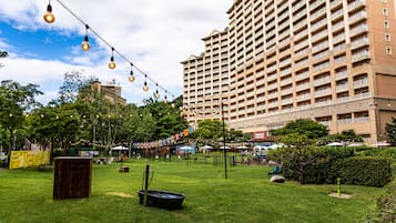 A courtyard with string lights, a fountain, and a large building in the background.