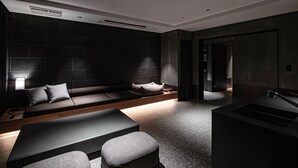 A modern, dark-themed living area with a sofa, ottomans, and a built-in TV. - Sono Pet Clubs & Resorts VivaldiPark (Hongcheon)