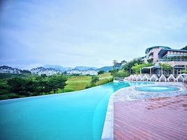 Un resort con piscina, terraza de madera y vistas a una cordillera.