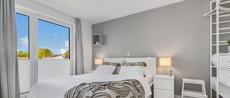 A bedroom with a bed, bedside tables, a nightstand, a small table, and a wardrobe.