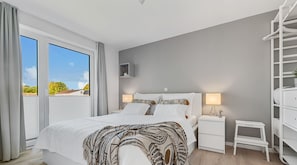 A bedroom with a bed, bedside tables, a nightstand, a small table, and a wardrobe.