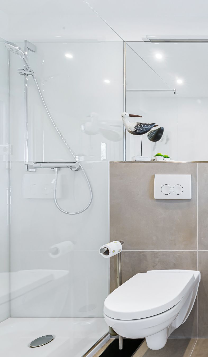 Ein modernes Badezimmer mit Duschkabine aus Glas, Toilette und Handtuchhalter.