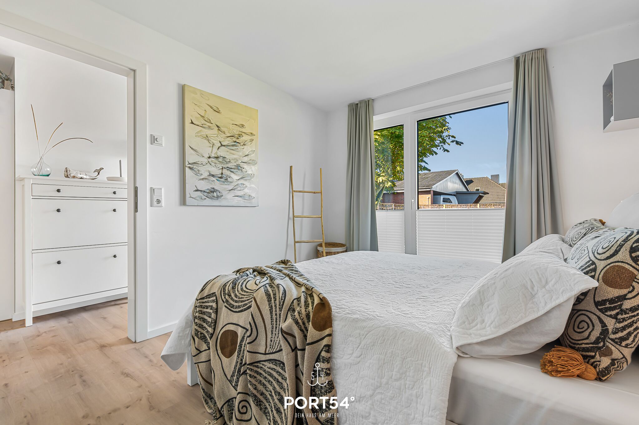 Une chambre à coucher avec un lit, une commode, une échelle et une fenêtre avec des rideaux.