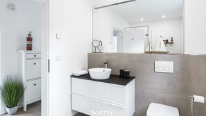Un bagno moderno con un mobile lavabo bianco, uno specchio grande e un water.