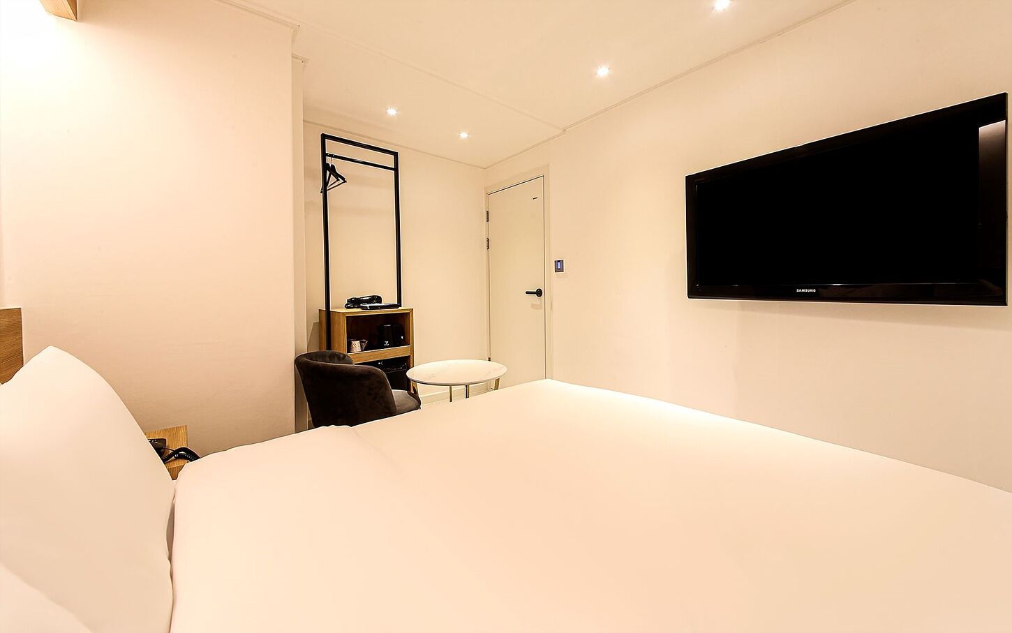 A hotel room with a bed, a round table, a chair, a TV, and a wardrobe.