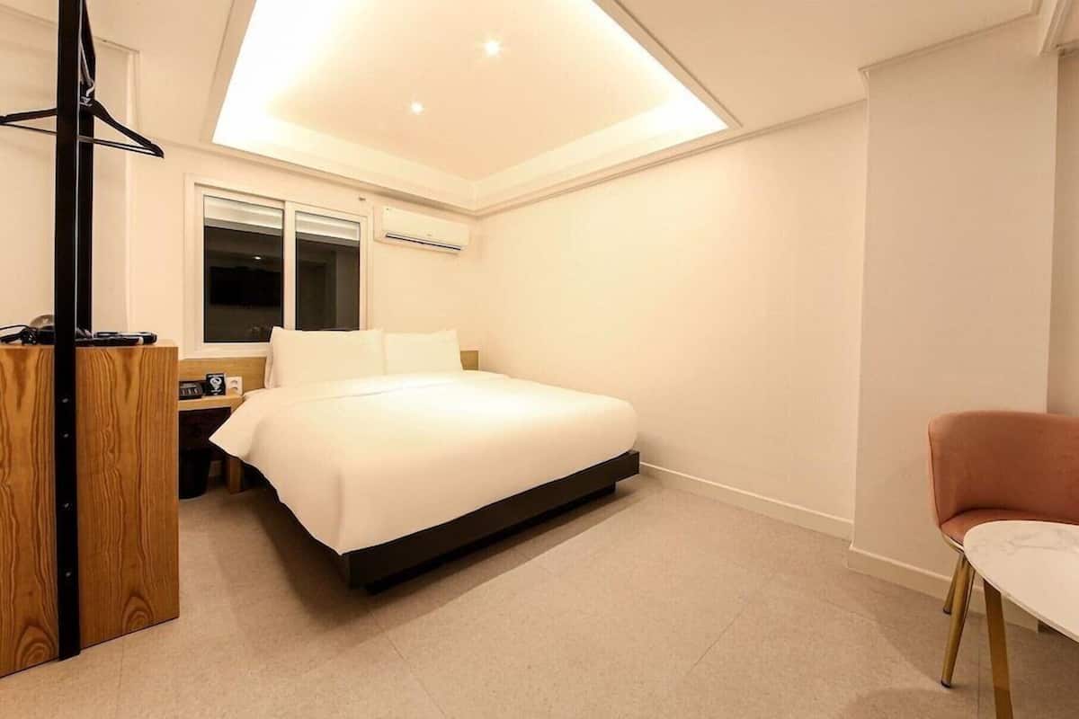 Ein modernes Hotelzimmer mit einem Bett, einem Schreibtisch, einem Stuhl und einem Oberlicht.