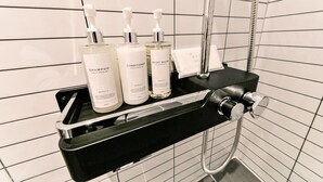 A bathroom with a black shelf holding three bottles of body wash and conditioner, a handheld showerhead, and a towel rack. - Busan Seomyeon Business Hotel J7 (Busan)