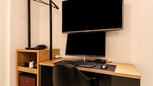 A wooden desk with a black chair, a computer setup including a monitor, keyboard, and mouse, and a shelf with a few items. - Busan Seomyeon Business Hotel J7 (Busan)