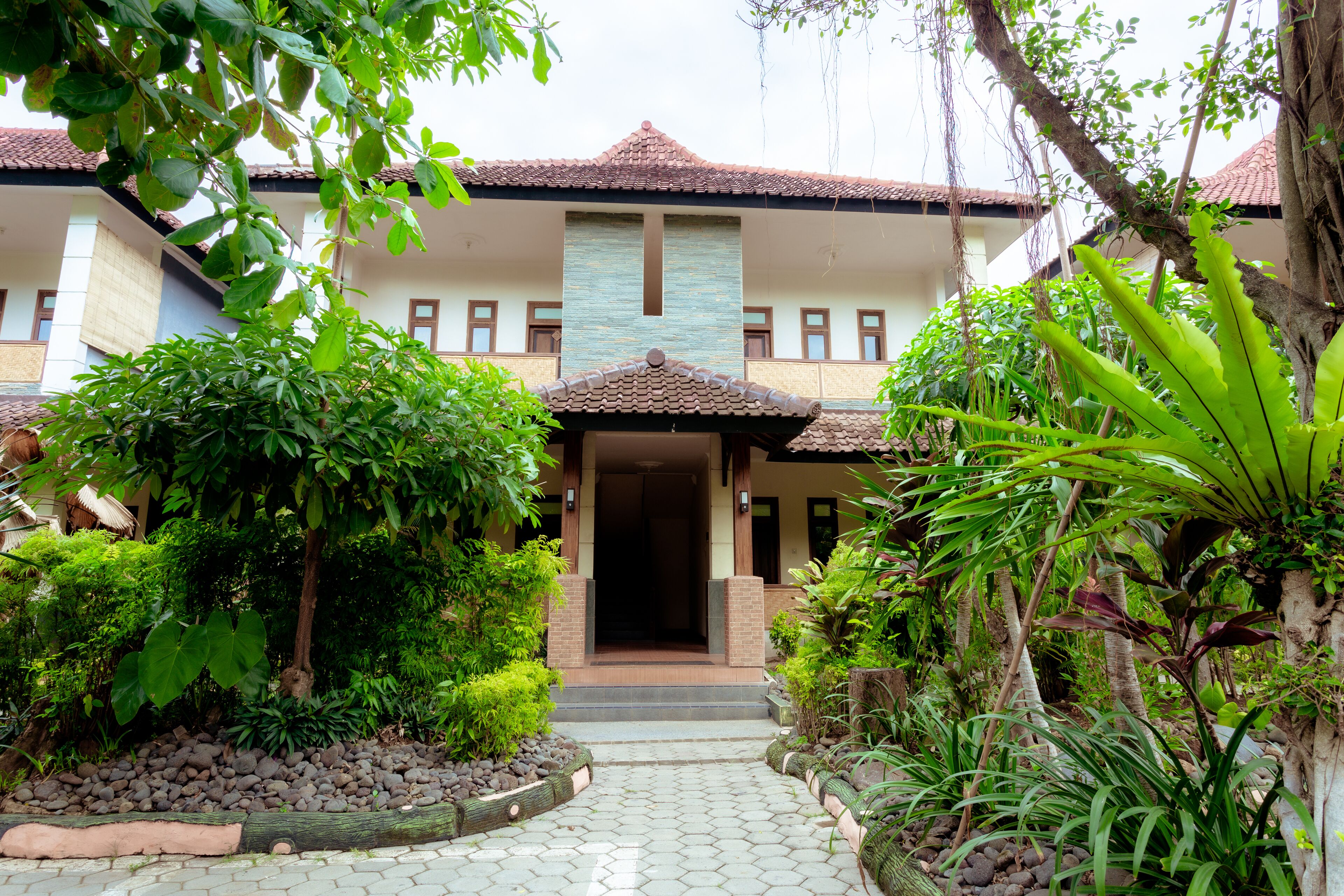 A building with a tiled roof, a central entrance, and surrounding greenery.