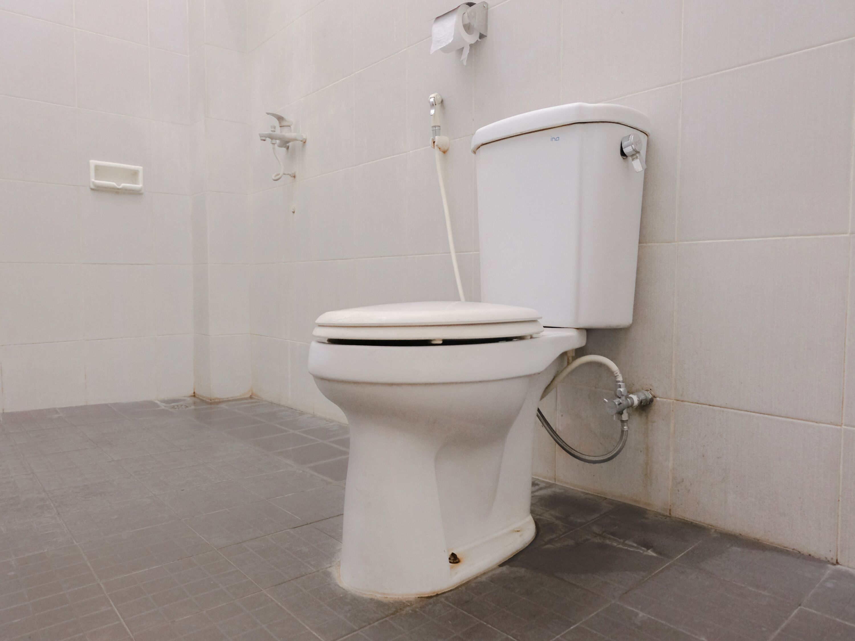 A white toilet in a bathroom with grey tiles.