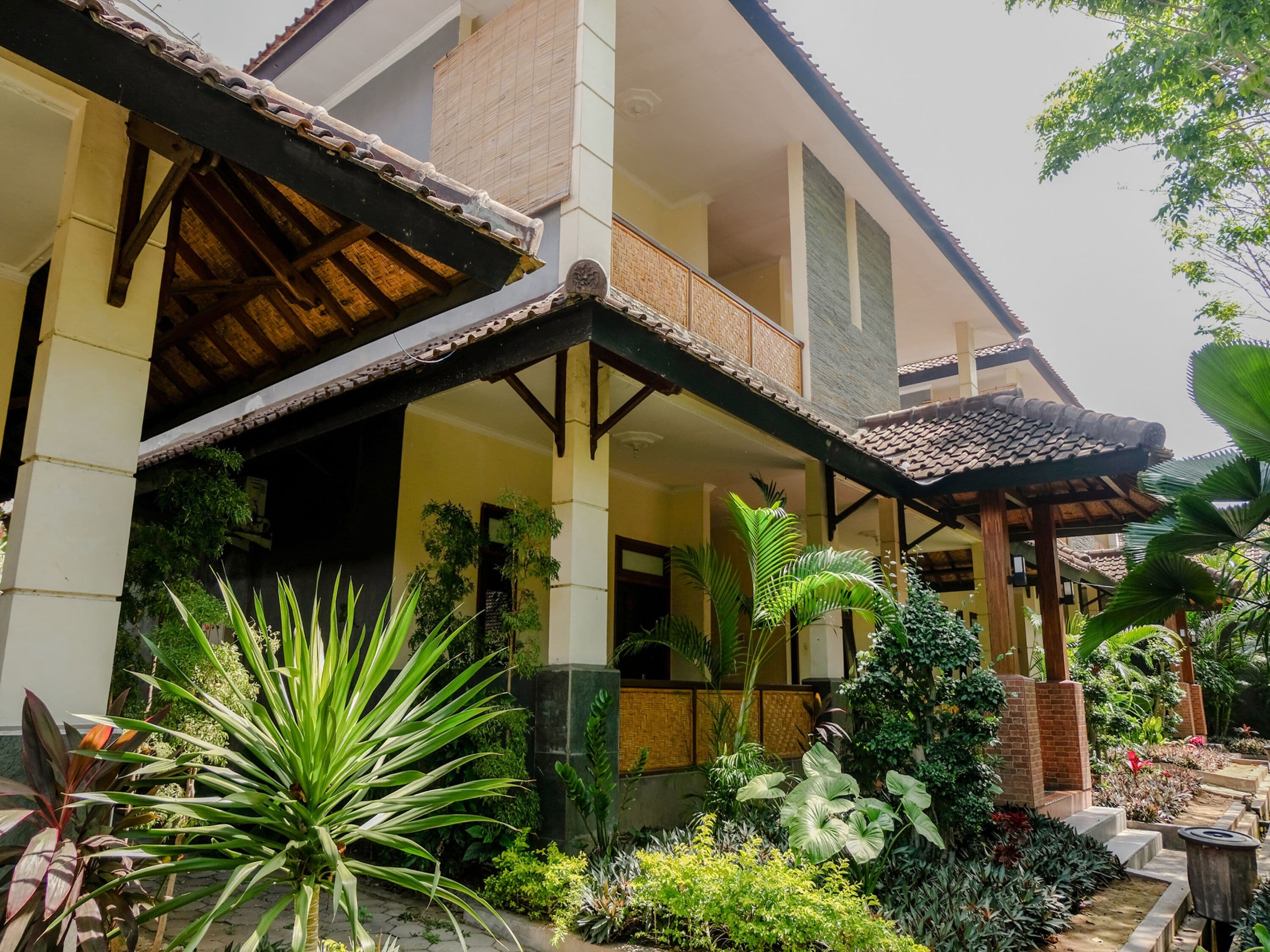 A traditional-style building with a covered porch and a garden with various plants.