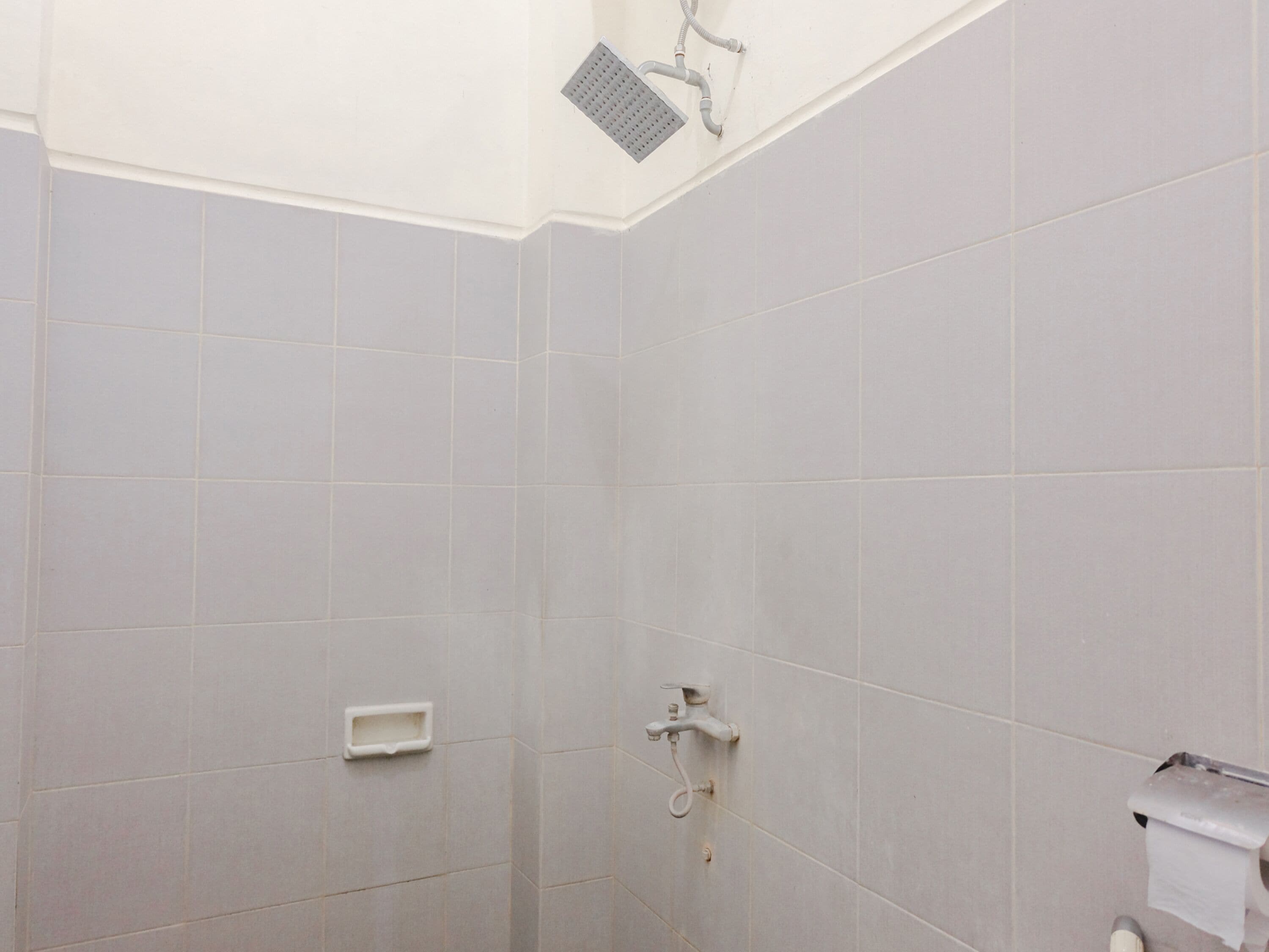 A bathroom with grey tiles, a shower, and a toilet.