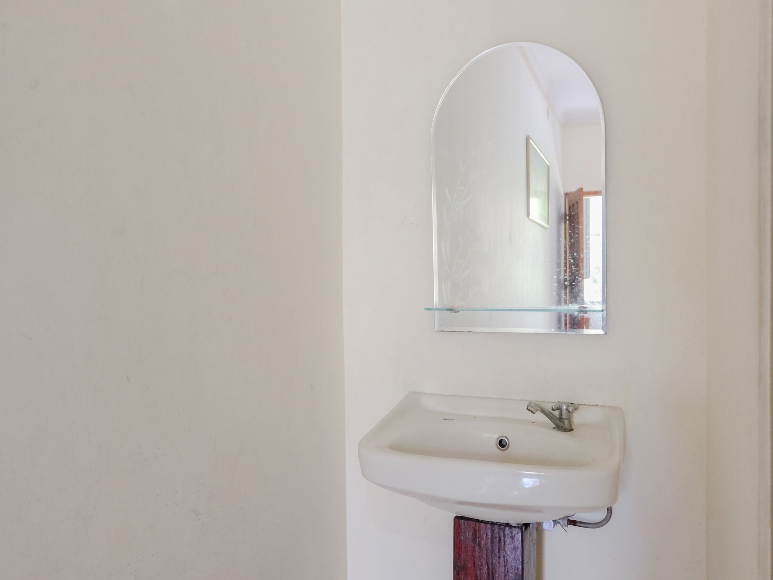 Une salle de bain avec un lavabo blanc et un miroir au-dessus.