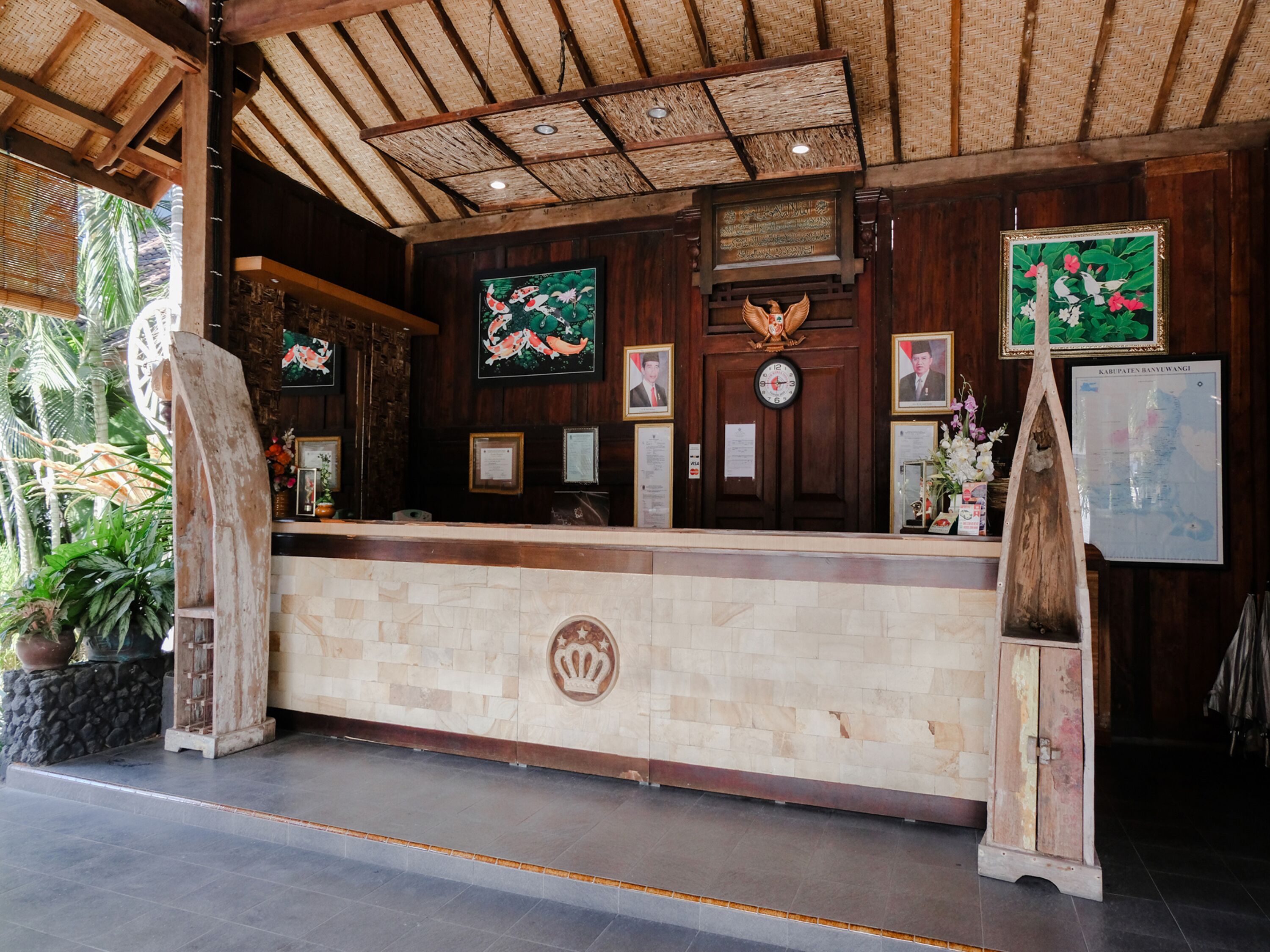 A reception area with a wooden reception desk, framed pictures, a clock, and a map on the wall.
