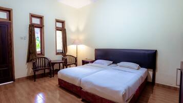 Un dormitorio con una cama doble, dos sillones, un escritorio y una lámpara.