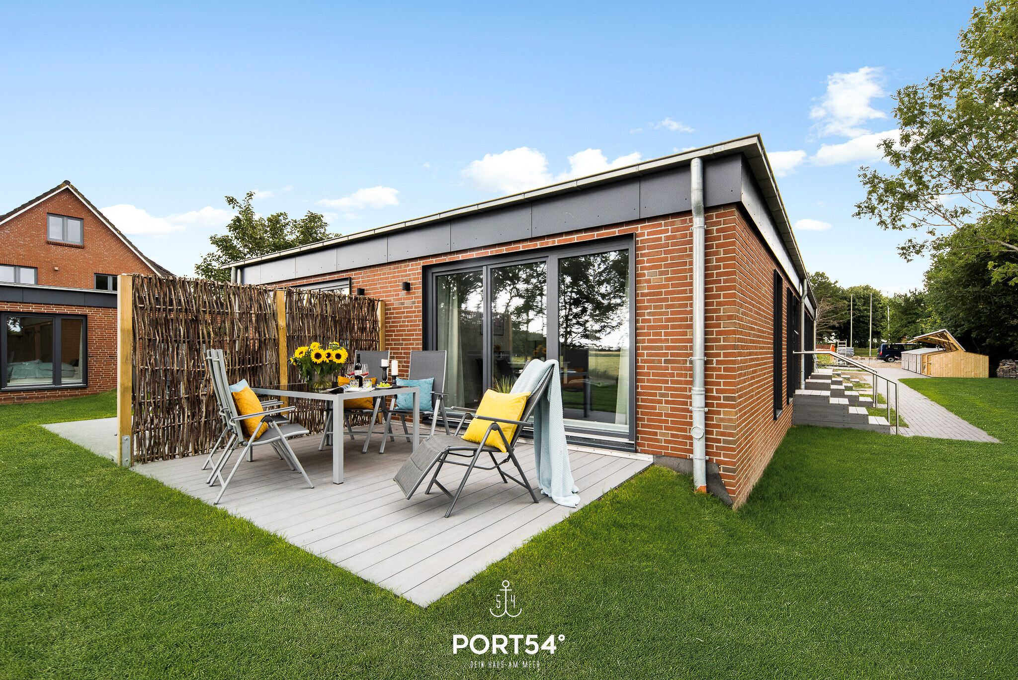 Ein modernes Haus mit Terrasse, Essbereich und einem großen Glasfenster.