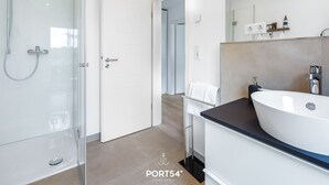 Ett modernt badrum med en duschavdelning med glasväggar, en vit tvättställ och en spegel ovanför tvättstället.