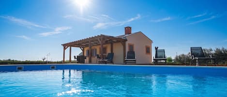 A pool with lounge chairs and a pergola structure.