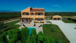 A two-story building with a covered patio, a swimming pool, and a garage. - Secluded Pool Villa Sofija Near Zadar (Škabrnja)