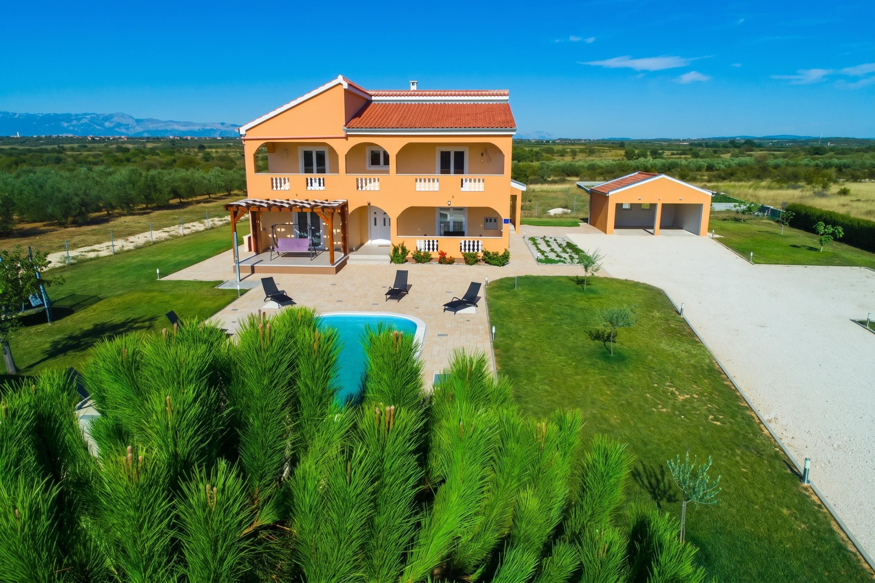 Une maison à deux étages avec une piscine, un espace salon extérieur et une vue sur le paysage environnant.