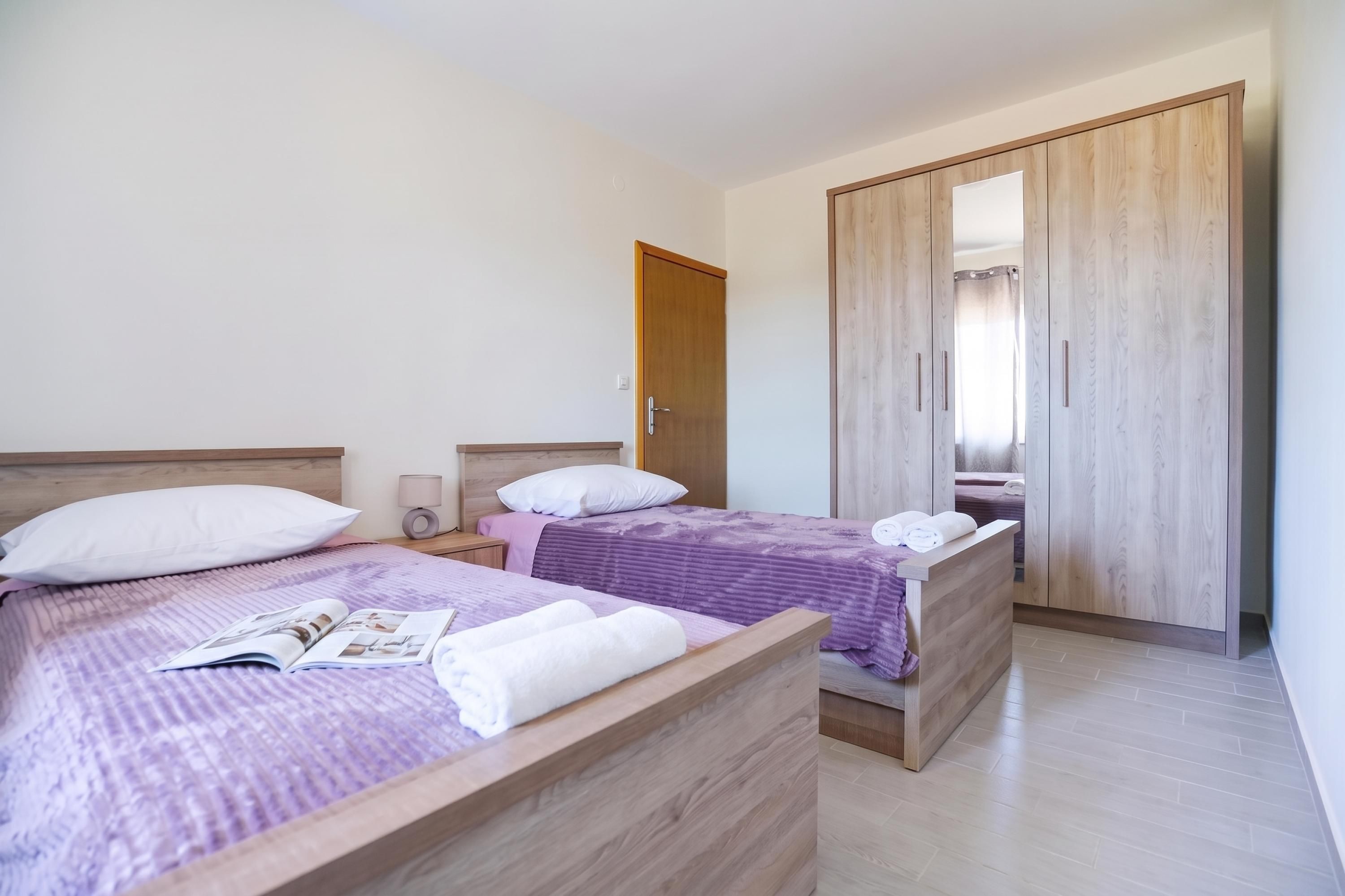 Un dormitorio con dos camas, un armario de madera y una mesita de noche con una lámpara.