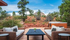 An outdoor seating area with wicker furniture, a central table, and a hot tub. - Stunning Luxury Home Thunder Mtn Views + Hot Tub! (Sedona)