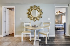 Un coin repas comprenant une table ronde, deux chaises et un miroir décoratif accroché au mur.
