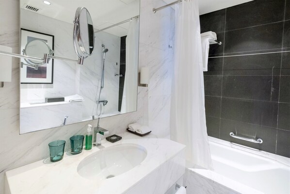 A modern bathroom with a large mirror, a white sink, and a bathtub.