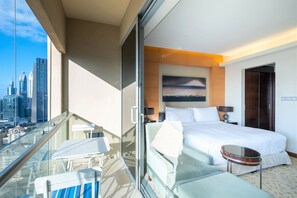 A hotel room with a bed, a small table, a sofa, and a balcony with a glass railing. - Amazing Stay & Burjview at The Address Dubai Mall (Dubai)