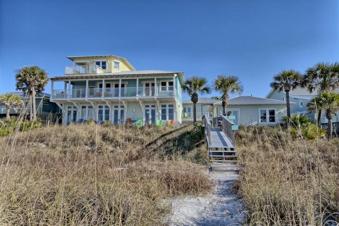 Une propriété située en bord de mer, comprenant une maison à plusieurs étages, une allée couverte et une végétation luxuriante.