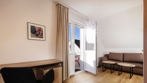 A modern room with a wooden desk, a black chair, a brown sofa, and two small tables. - Hummerklippen Apartments (Helgoland)