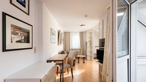 A modern kitchen with a dining area, wooden flooring, and a large window. - Hummerklippen Apartments (Helgoland)