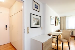 Una habitación de hotel moderna con suelo de madera, un escritorio con silla, un radiador y cuadros en la pared.