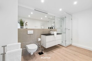 Ein modernes Badezimmer mit Toilette, Waschbecken und Duschkabine aus Glas.