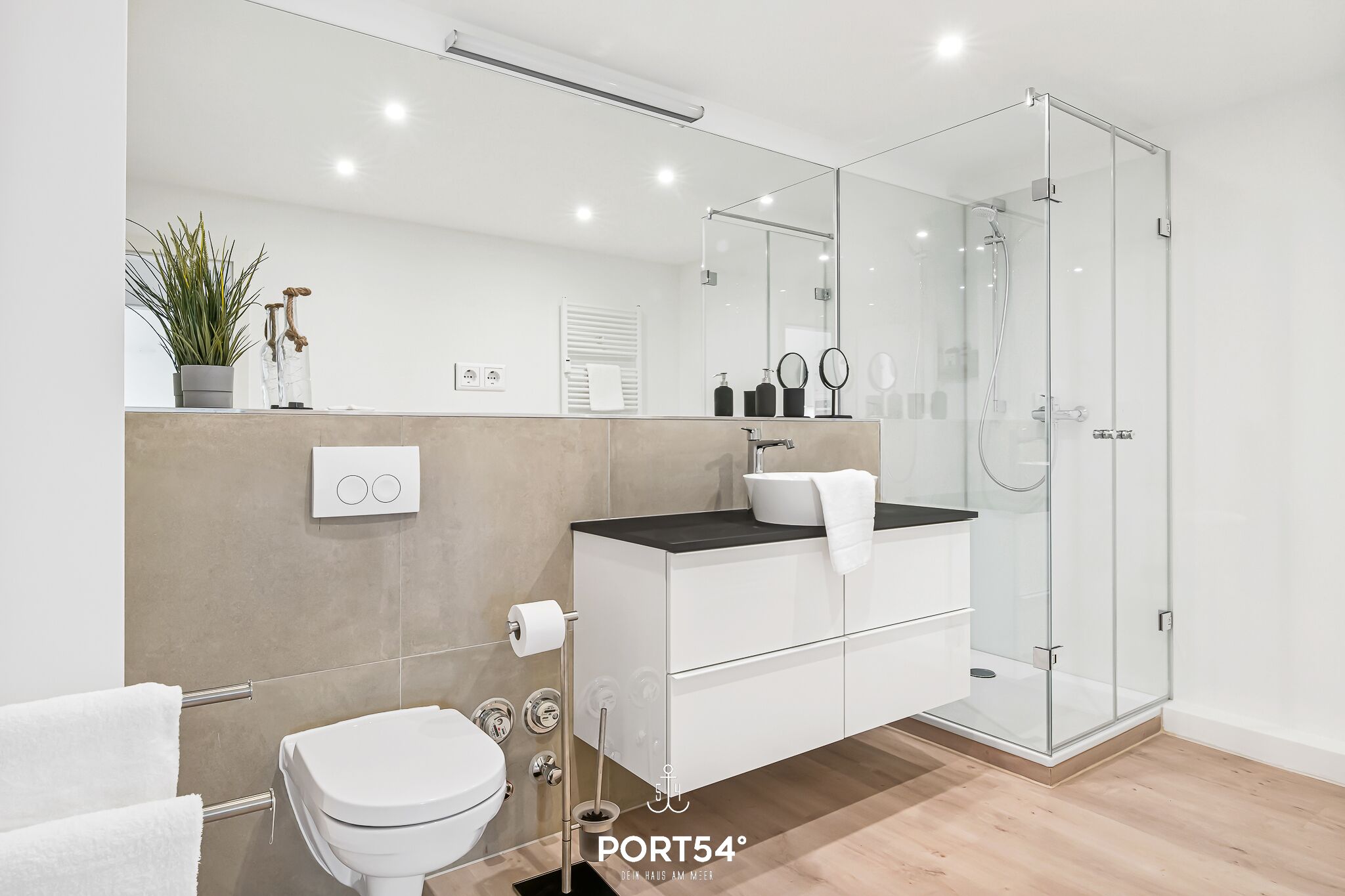 A modern bathroom with a toilet, sink, and glass-enclosed shower.