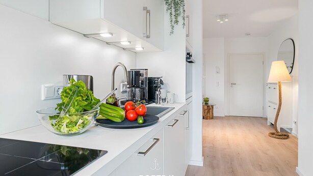 A modern kitchen with white cabinetry, a black countertop, and a black induction cooktop. - Hohe Wacht – for 6 people, rural, idyllic, North Sea (Emmelsbüll)