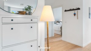 A modern room with a white dresser, a lamp, a mirror, and a wooden floor. - Hohe Wacht – for 6 people, rural, idyllic, North Sea (Emmelsbüll)
