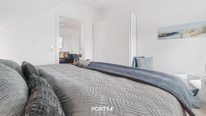 A modern bedroom with a large bed, a side table, and a painting on the wall. - Hohe Wacht – for 6 people, rural, idyllic, North Sea (Emmelsbüll)