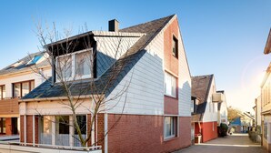 A residential building with a sloped roof, brick facade, and a small tree in the foreground. - Hummerklippen Ferienwohnungen (Helgoland)