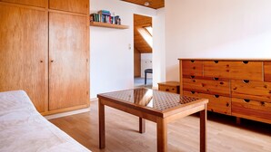 A bedroom with a wooden wardrobe, a small table, and a dresser. - Hummerklippen Ferienwohnungen (Helgoland)