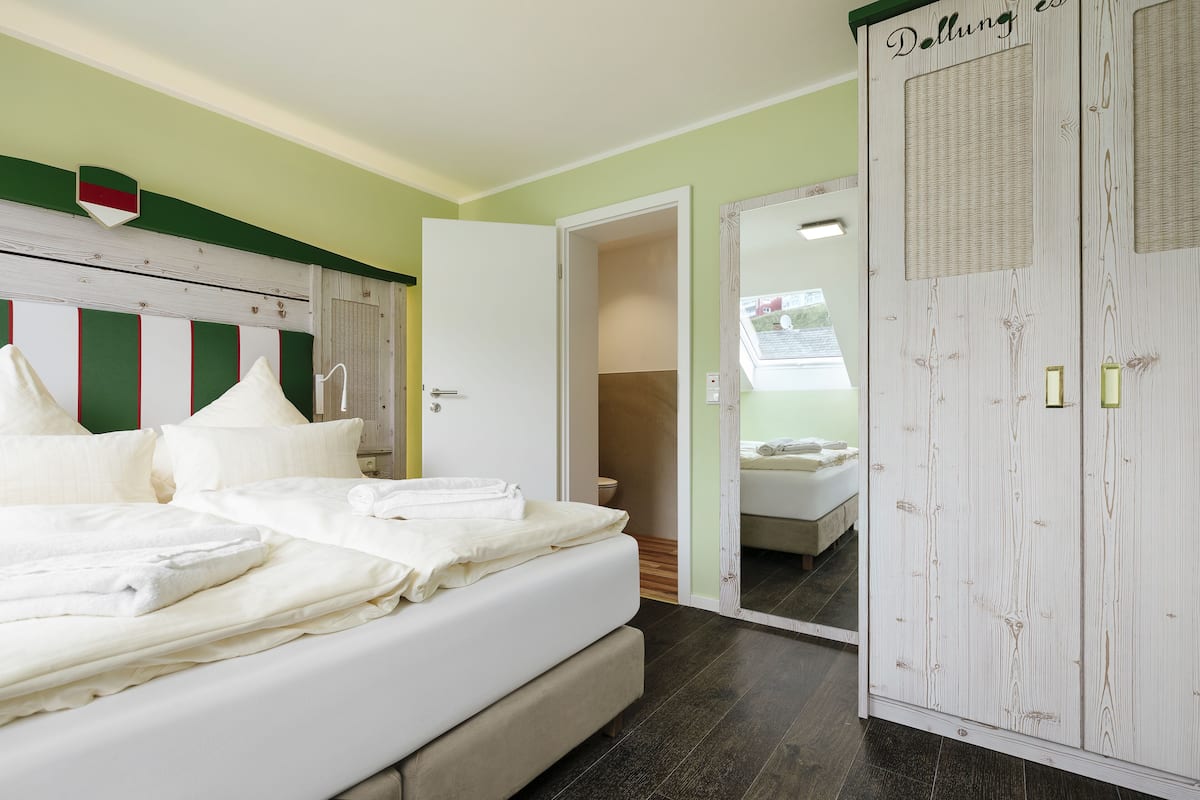 A hotel room with a bed, a wardrobe, and a bathroom visible through an open door.