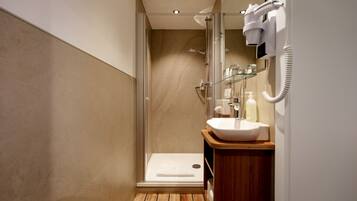 A modern bathroom with a glass shower enclosure, a wooden vanity, and a white sink.