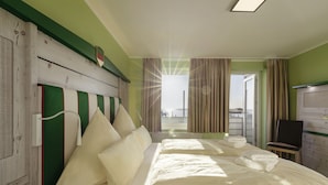 A hotel room with a large bed, a wooden headboard, a desk, and a view of the sea. - Insulaner Ferienwohnungen (Helgoland)