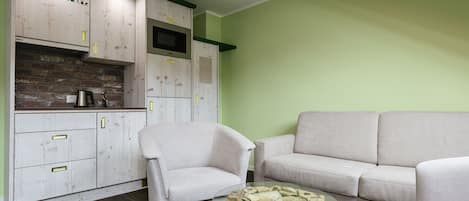 Ein modernes Wohnzimmer mit einem weißen Sofa, einem Glastisch und einem Holzschrank mit einer grünen Akzentwand.