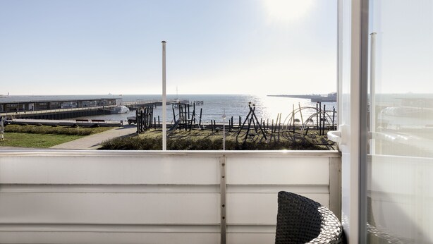 A view from a window overlooking a marina with boats, a dock, and a clear sky. - Insulaner Ferienwohnungen (Helgoland)