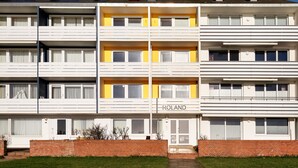 A multi-story residential building with balconies, a brick facade, and a visible name "ROLAND" on the ground floor. - Haus Roland (Helgoland)