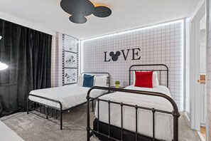 Et soveværelse med to senge, væg med et rutemønster og et stort 'LOVE'-skilt.