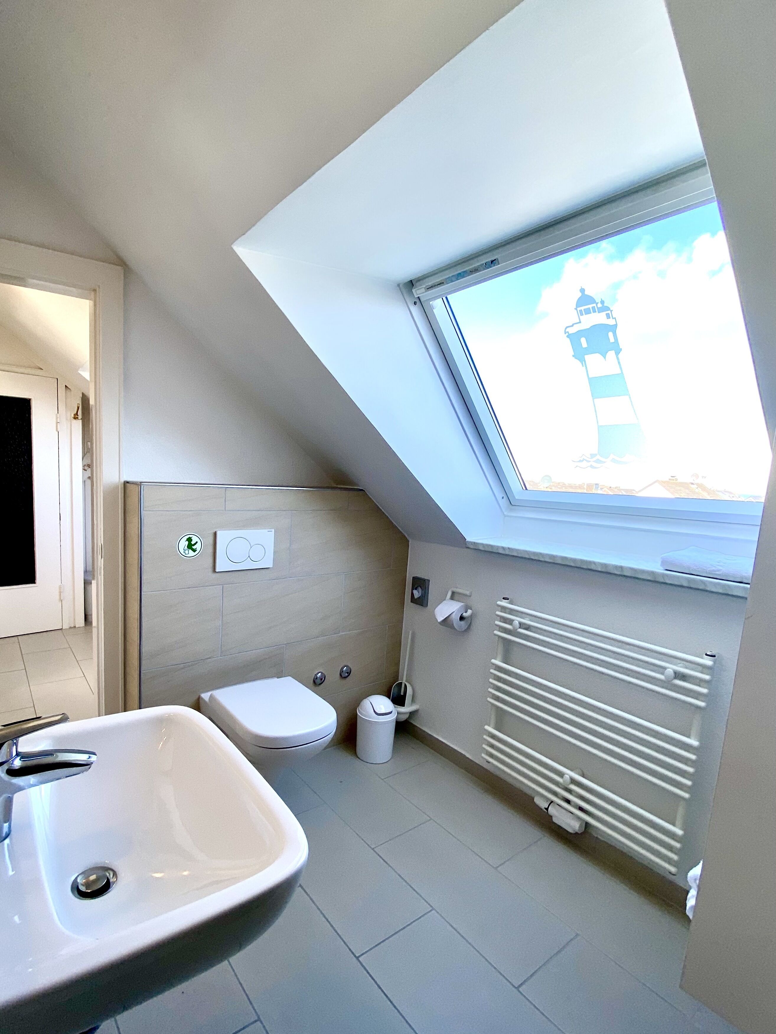 A modern bathroom with a skylight, a toilet, a sink, and a radiator.
