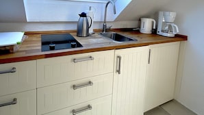 A kitchen with a skylight, a sink, a coffee maker, and cabinets. - Haus Germania (Helgoland)