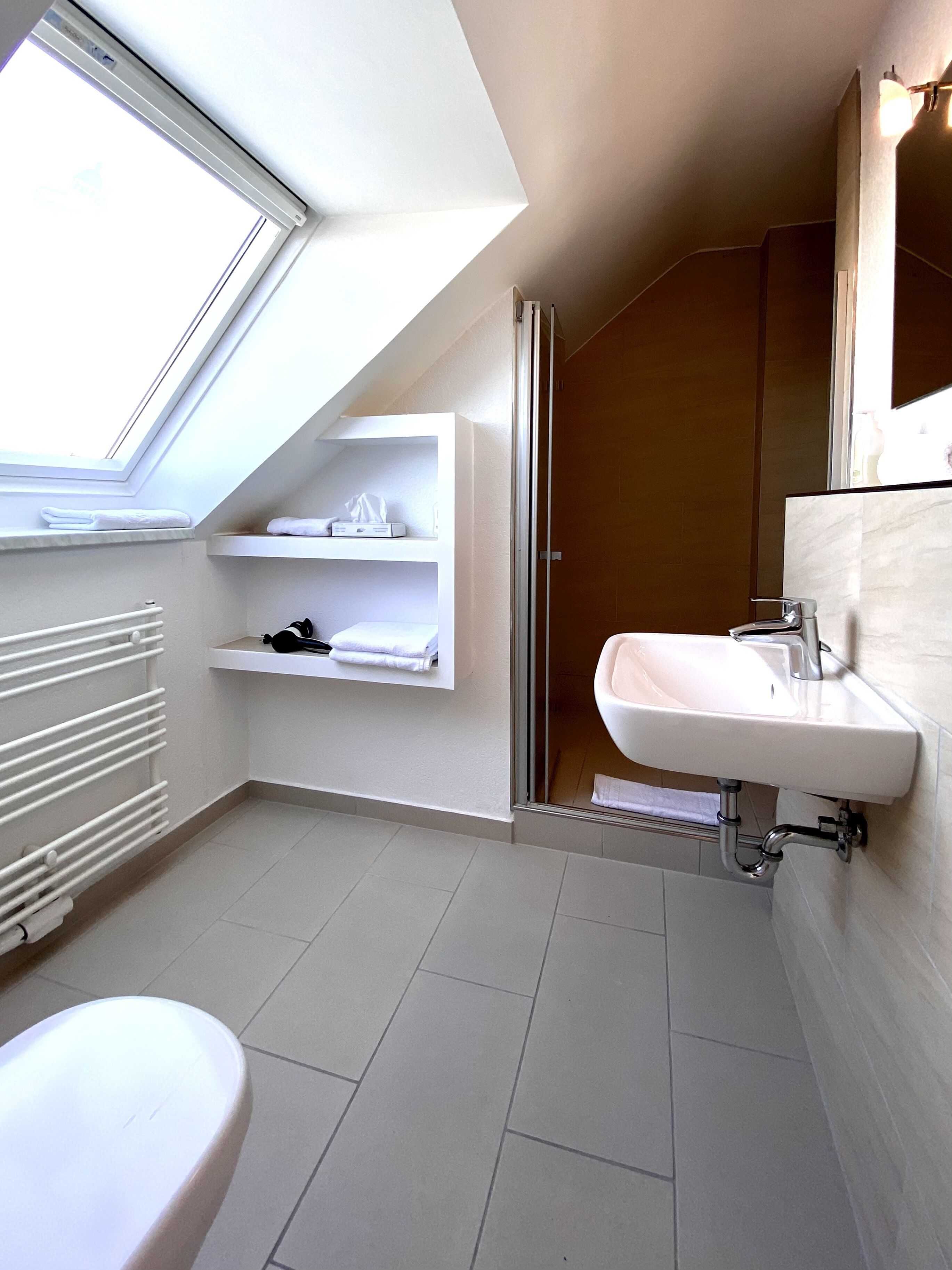 Ein modernes Badezimmer mit Oberlicht, einem weißen Waschbecken und einer Toilette.